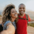 Alexis Edwards smiles with a friend as they take a selfie together outdoors on a scenic hiking trail.