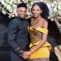 Edith and Dele pose together in matching black and yellow leopard print outfits before a floral and dried palm leaf arch.